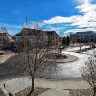 A quiet neighborhood with houses lining the curved street under a blue sky.