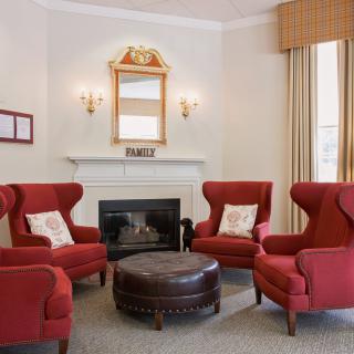 A cozy living room featuring red armchairs, a fireplace, and a decorative mirror.