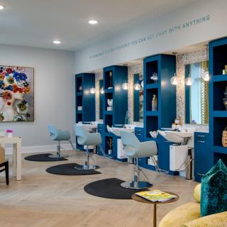 A modern hair salon with stylish chairs, large mirrors, and vibrant artwork.