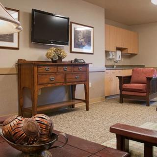 A cozy living room with a television, armchair, and wooden cabinet.