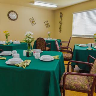 A cozy dining area set with green tablecloths and floral decorations.