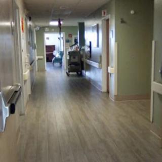 A view of a hospital corridor with medical equipment and rooms along the sides.