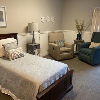 A cozy bedroom with a single bed, two armchairs, and tasteful decor.