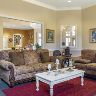 A cozy living room with patterned sofas, a white coffee table, and decorative elements.