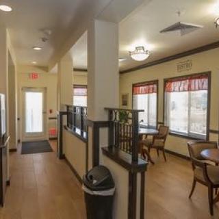 A cozy interior hallway with tables and chairs by the windows.