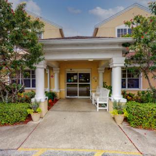 The inviting entrance to a hotel, featuring elegant columns and lush landscaping.