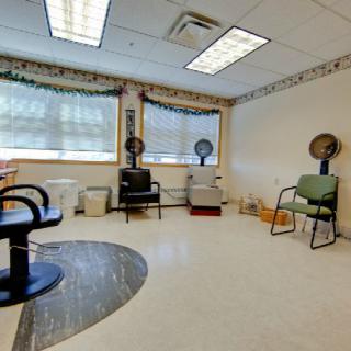 A brightly lit salon interior with chairs and hair dryers.