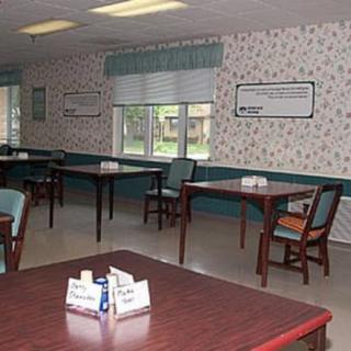 An empty dining area with tables and chairs, decorated with floral wallpaper.