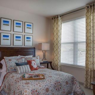 Cozy bedroom interior with a neatly made bed, decorative pillows, and framed artwork on the wall.