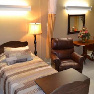 Cozy bedroom with a single bed, armchair, and warm lighting.