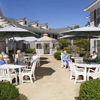 Seniors enjoying a sunny day on the patio of a retirement home.