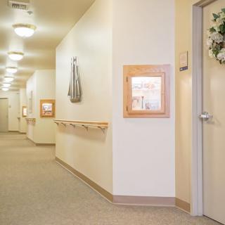 A well-lit hallway with doors and framed decorations on the walls.