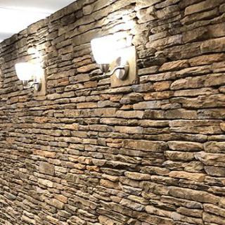 A dimly lit stone wall with elegant sconces enhancing its rustic charm.