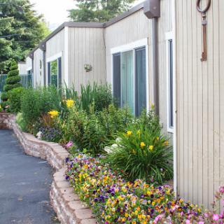 A beautifully landscaped area beside a residential building, featuring vibrant flowers and greenery.
