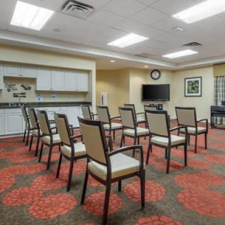 An empty conference room with rows of chairs facing a television and presentation area.