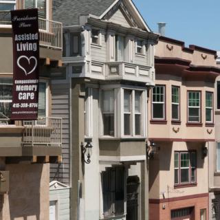 A row of residential buildings with varied architectural styles and a banner advertising senior living.