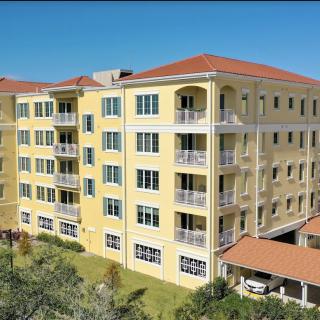 A multi-story apartment building with a yellow facade and red-tiled roof.