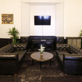 A modern lounge area featuring leather sofas, a central coffee table, a mounted TV, and decorative plants.