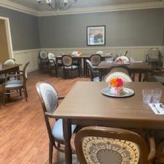 A neatly set dining room with several tables and chairs on a wooden floor.