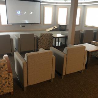 A cozy movie room with comfortable seating arranged in front of a large screen.