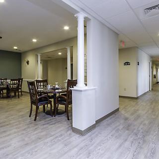 A modern dining area with tables and chairs, featuring wood flooring and column accents.