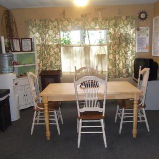 A cozy dining area with a wooden table and chairs, surrounded by cabinets and floral curtains.