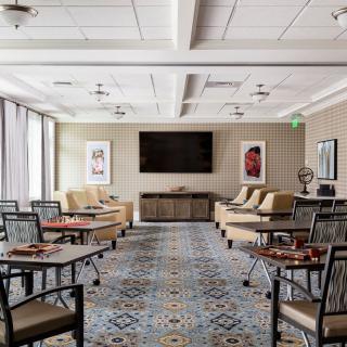 A spacious lounge area featuring tables, chairs, and a large television.