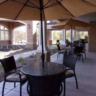 A spacious outdoor patio with tables, chairs, and umbrellas for shade.