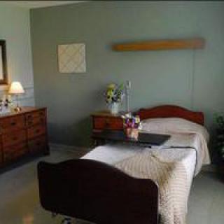 A clean and organized hospital room featuring a single bed with a bedside table and cozy lighting.
