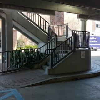 A view of a staircase located inside a parking garage, featuring multiple levels and decorative railings.