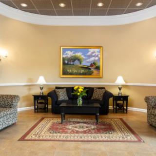 A well-decorated lobby area featuring a sofa, armchairs, coffee table, and wall art.