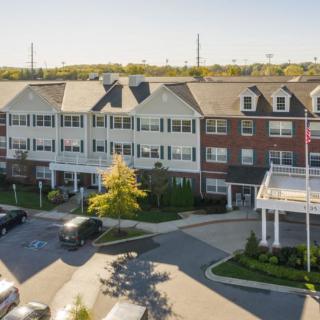 A residential building with a parking lot and surrounding greenery.