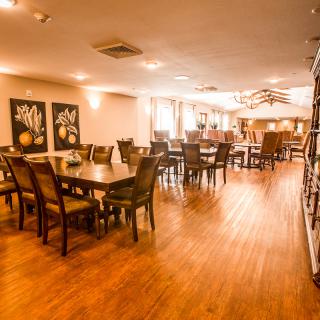 Spacious dining area with wooden tables and chairs, complemented by warm lighting and artwork on the walls.