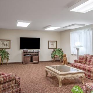 A cozy living room with patterned sofas, a coffee table, and a large television.