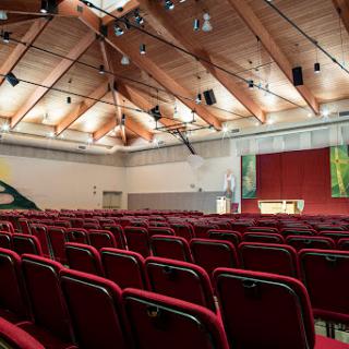 A spacious auditorium with red seating and a wooden ceiling, ready for an event.