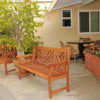 A cozy outdoor patio with wooden benches and a table beside a tree and plants.