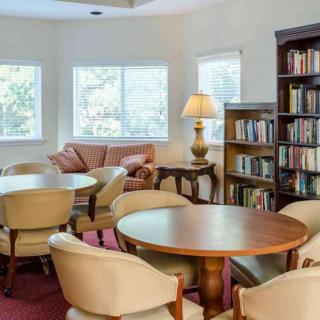 A cozy reading room with bookshelves, tables, and comfortable seating.
