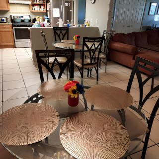 A cozy kitchen and dining area with a table set for dining, featuring placemats and a vase with flowers.