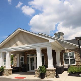 A sunny day at the entrance of a building with columns and a porch.