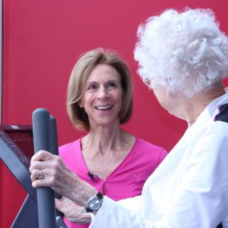 Two women engaging in a conversation while exercising at the gym.