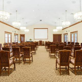 A spacious conference room setup with rows of chairs facing a presentation screen.