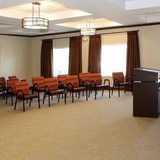 An empty conference room with rows of chairs and a podium at the front.