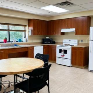 A spacious kitchen with wooden cabinets, a dining table, and modern appliances.
