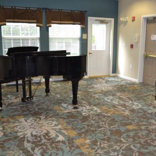 A music room featuring a grand piano and decorative carpet.