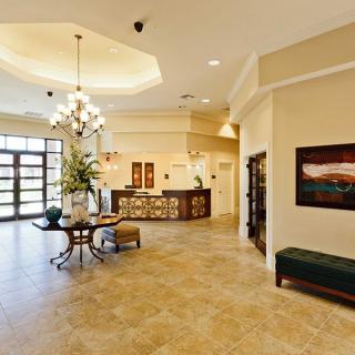 A modern and spacious lobby with a reception desk, chandelier, and comfortable seating.