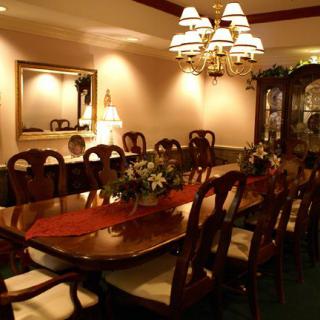 An elegant dining room with a long wooden table, multiple chairs, and a chandelier.