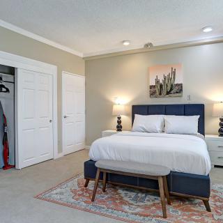 A cozy bedroom with a neatly made bed, stylish lamps, and elegant decor.