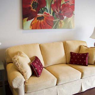 A cozy living room setup with a beige sofa and vibrant red floral artwork.