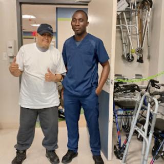 A patient and a healthcare professional pose together in a rehabilitation setting.