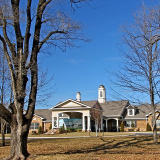 A large, elegant building surrounded by trees and a clear blue sky.
